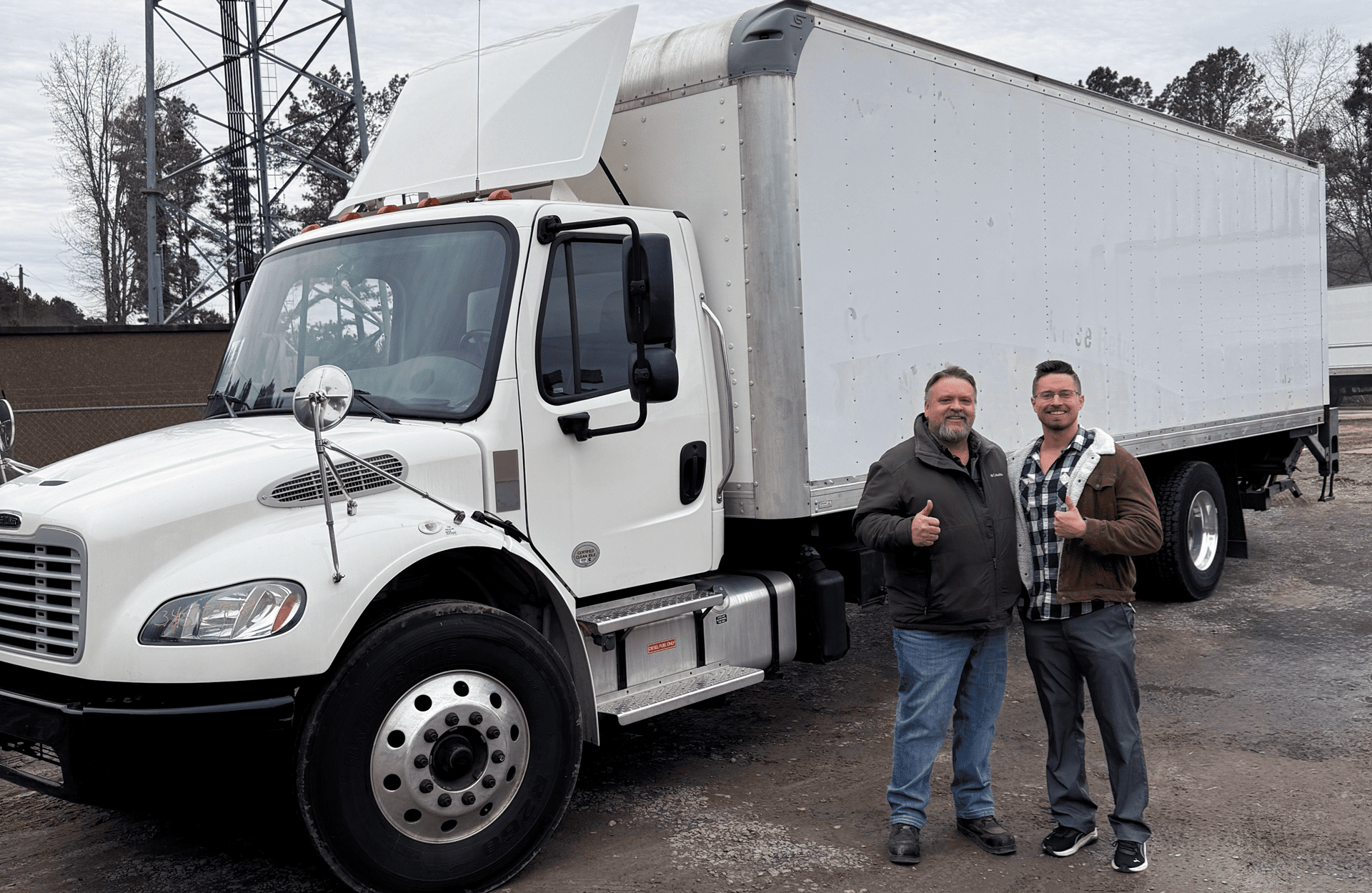 Owner with purchaser standing beside a white commercial box truck at US Truck & Body LLC.
