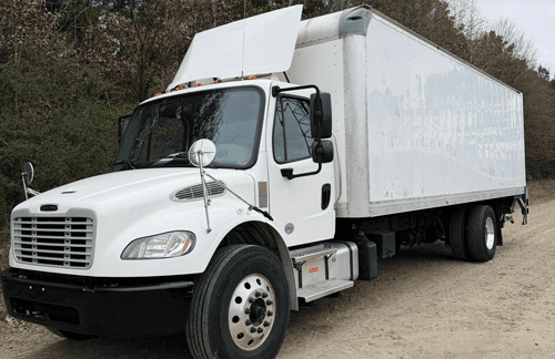 white box truck sitting on a gravel road 