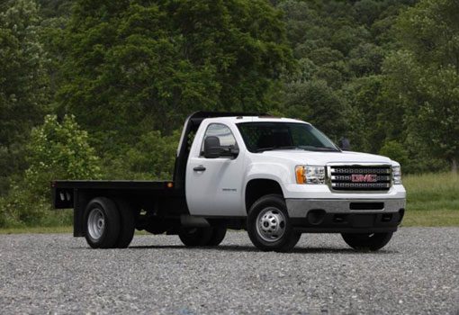 white GMC flatbed hauling truck parked on gravel