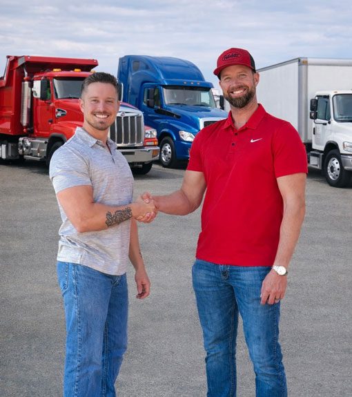 Zach and Andrew shaking hands in front of 3 trucks